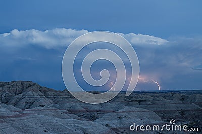 Lightning strikes the horizon over an eerie landscape in the Badlands National Park. Stock Photo