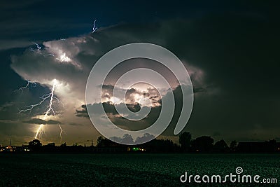Lightning strikes down from the top of the thunderstorm, outside the storm cloud Stock Photo