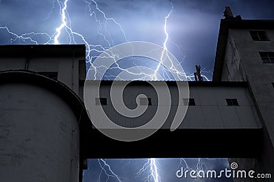 Lightning and thunder on stormy summer night over factory Stock Photo