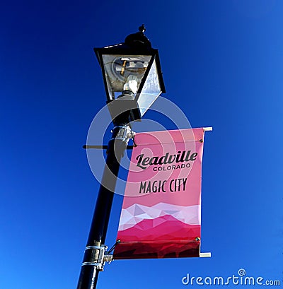 Lightpole with pink `Leadville Colorado Magic City` sign showing mountains at the bottom in white and pink shades Editorial Stock Photo