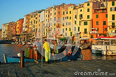 Men working to collect garbage at dawn on the pier of the port overlooking the colored buildings of Portovenere Editorial Stock Photo