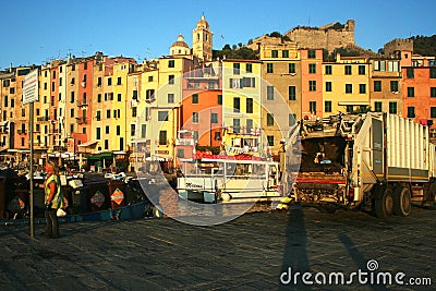Men working to collect garbage at dawn on the pier of the port overlooking the colored buildings of Portovenere Editorial Stock Photo