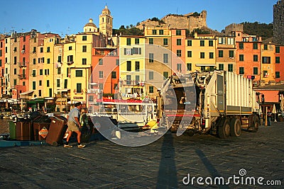 Men working to collect garbage at dawn on the pier of the port overlooking the colored buildings of Portovenere Editorial Stock Photo