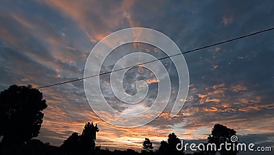 Like a gate that opens the sunset sky is surrounded by chaotic clouds that reflect a beautiful golden color Stock Photo