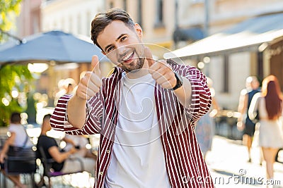 Happy man showing thumbs up, like sign positive something good positive feedback in city street Stock Photo