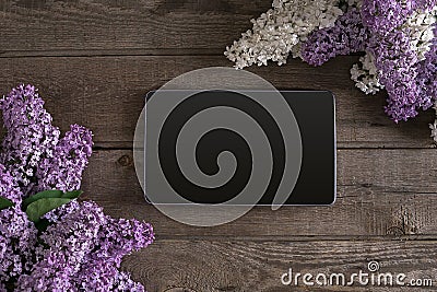 Lilac blossom on rustic wooden background, tablet with empty space for greeting message. Top view Stock Photo
