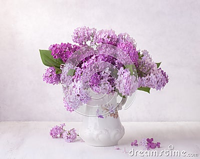 Lilac bouquet in the faience jug on a white wooden table. Soft focus Stock Photo