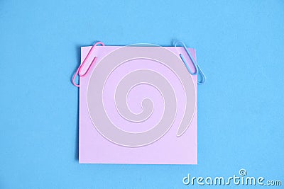 Lilac paper stickers for writing notes on a blue background. Stock Photo