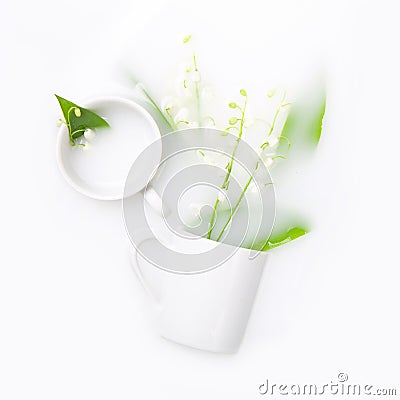 Lilies of the valley in white cups float in milk. The concept of purity, tenderness, freshness Stock Photo