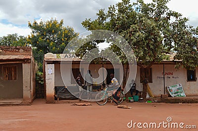 LILONGWE, MALAWI, AFRICA - APRIL 1, 2018: Africans are sitting at house, speaking with woman on the bycicle along the road where Editorial Stock Photo