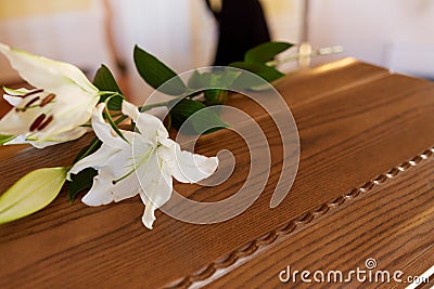 Lily flower on wooden coffin at funeral in church Stock Photo