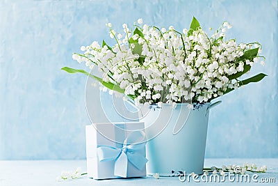 Lily of the valley flowers in blue vase and gift box on rustic table. Greeting card for woman day. Stock Photo