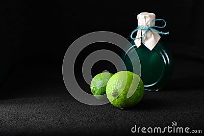 LIME ON A BLACK BACKGROUND WITH A BOTTLE OF LIME OIL Stock Photo
