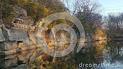 Rocky cliff overhanging River reflects seamlessly Stock Photo
