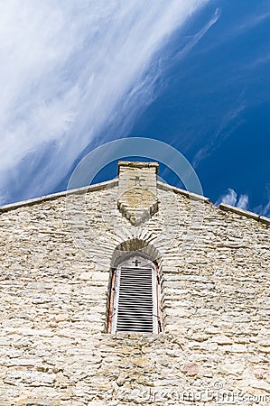 Limestone facade of ancient church with window shutter and cross Stock Photo