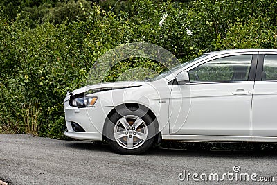 Crash damaged white car parked by a hedge.. Editorial Stock Photo