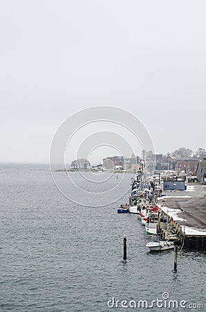 Line of colorful houses next to the harbor filled with boats on the water with a wind mill in a background Stock Photo