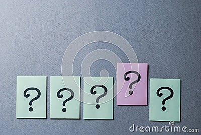 Line of five printed question marks on grey Stock Photo