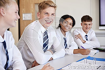 Line Of High School Students Wearing Uniform Sitting At Desk In Classroom Stock Photo