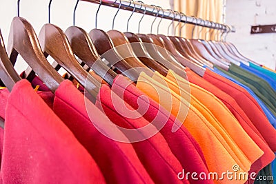 Line of multi colored clothes on wooden hangers in store. Sale Stock Photo