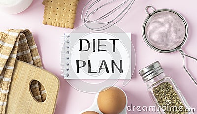 Notepad with Diet Plan list text on chopping board with wooden fork and spoon and measuring tape on pink table , recipes food Stock Photo
