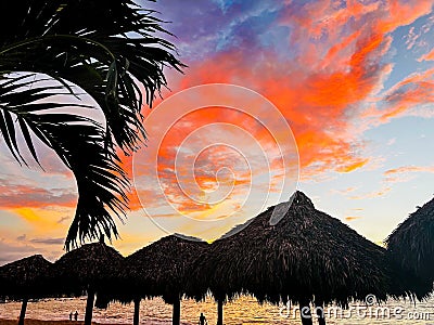 Tropical sunset with thatched huts and palm trees Stock Photo