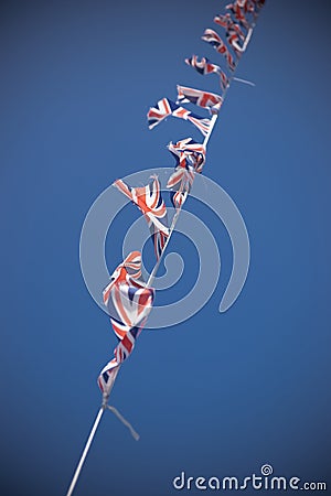 A line of Union Flag Union Jack bunting blowing in the wind against a blue sky Editorial Stock Photo