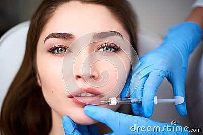 Lip Augmentation. Closeup Of Beautician Doctor Hands Doing Beauty Procedure To Female Lips with Syringe. Young Woman`s Stock Photo