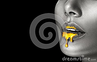 Lipstick dripping. Paint drips, lipgloss dripping from sexy lips, liquid Gold metallic paint drops on beautiful model girl`s mouth Stock Photo