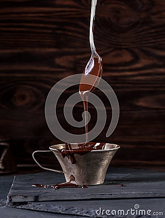 Liquid chocolate dripping from spoon into cup Stock Photo