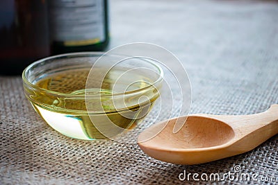 Liquid coconut MCT oil in round glass bowl with wooden spoon and Stock Photo