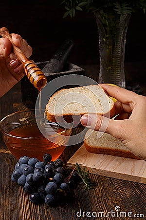 The liquid honey flows from the honey stick on a slice of bread Stock Photo