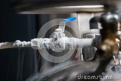 Liquid nitrogen frozen faucet and lever. Visible floating white condensation smoke from pressurized tank close up shot Stock Photo