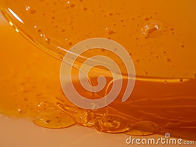 Liquid shower gel flows gracefully across a bright orange background. Stock Photo