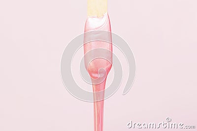 liquid wax for pink depilation drains from the stick. The concept of depilation, waxing, Stock Photo