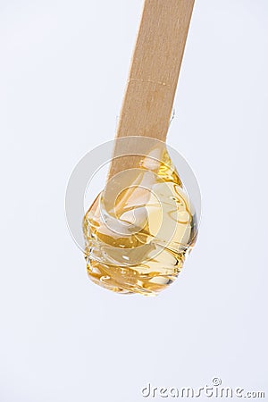 Liquid yellow sugar paste or wax for depilation on a stick close-up on a white background Stock Photo