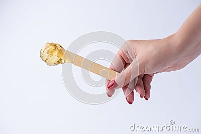 Liquid yellow sugar paste or wax for depilation on a stick close-up on a white background Stock Photo