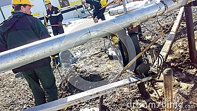 Liquidation of the oil spill. Locksmiths are engaged in eliminating oil leakage and repairing equipment. Workers liquidate the oil Editorial Stock Photo