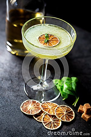 Liquor bottle, cocktail glass, brown sugar, basil leaves and dried lemon slices Stock Photo
