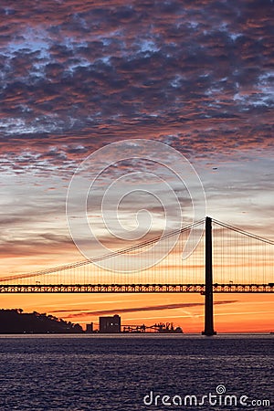 Lisbon 25th of April Bridge at sunset and industrial cranes at the background Stock Photo