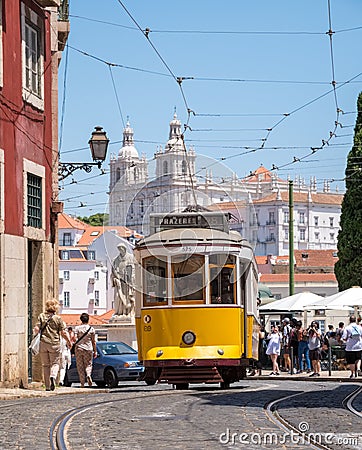 A Lisbon tram carrying passengers in the city with St. Vincent Church in the background Editorial Stock Photo