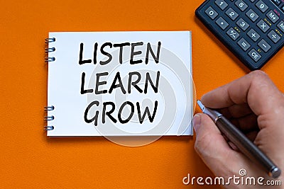 Listen, learn, grow symbol. Businessman writing words Listen, learn, grow on white note. Black calculator. Beautiful orange Stock Photo