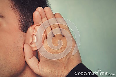 Listening male holds his hand near his ear. concept of deafness or eavesdropping. Hard of hearing Stock Photo
