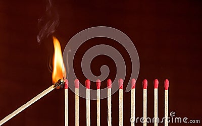 Lit match next to a row of unlit matches Stock Photo