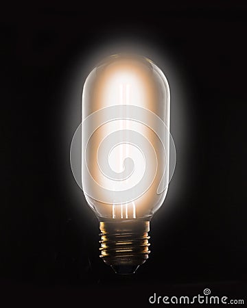 Lit tungsten filament light bulb on a black background Stock Photo