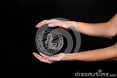 Litecoin coin and a man`s hand on a black background Stock Photo