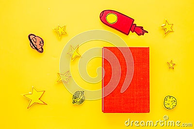 Literature for children. Fantactic, fiction story. Book with blank cover near cutout of rocket, stars, moon on yellow Stock Photo