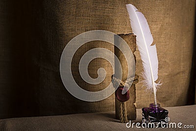 Literature concept. Old inkstand with feather near scroll and on canvas background Stock Photo
