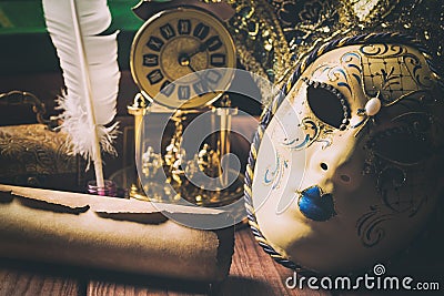 Literature concept. Still life with feather in inkstand, scroll, venetian mask, old books,vintage clock and box on wooden table. V Stock Photo