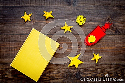 Literature about cosmos for school children. Book with blank cover near cutout of rocket, stars, moon on dark wooden Stock Photo